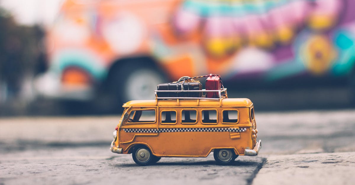 Close-up of a toy Volkswagen van with luggage, set against a colorful street backdrop, evoking summer travel vibes.